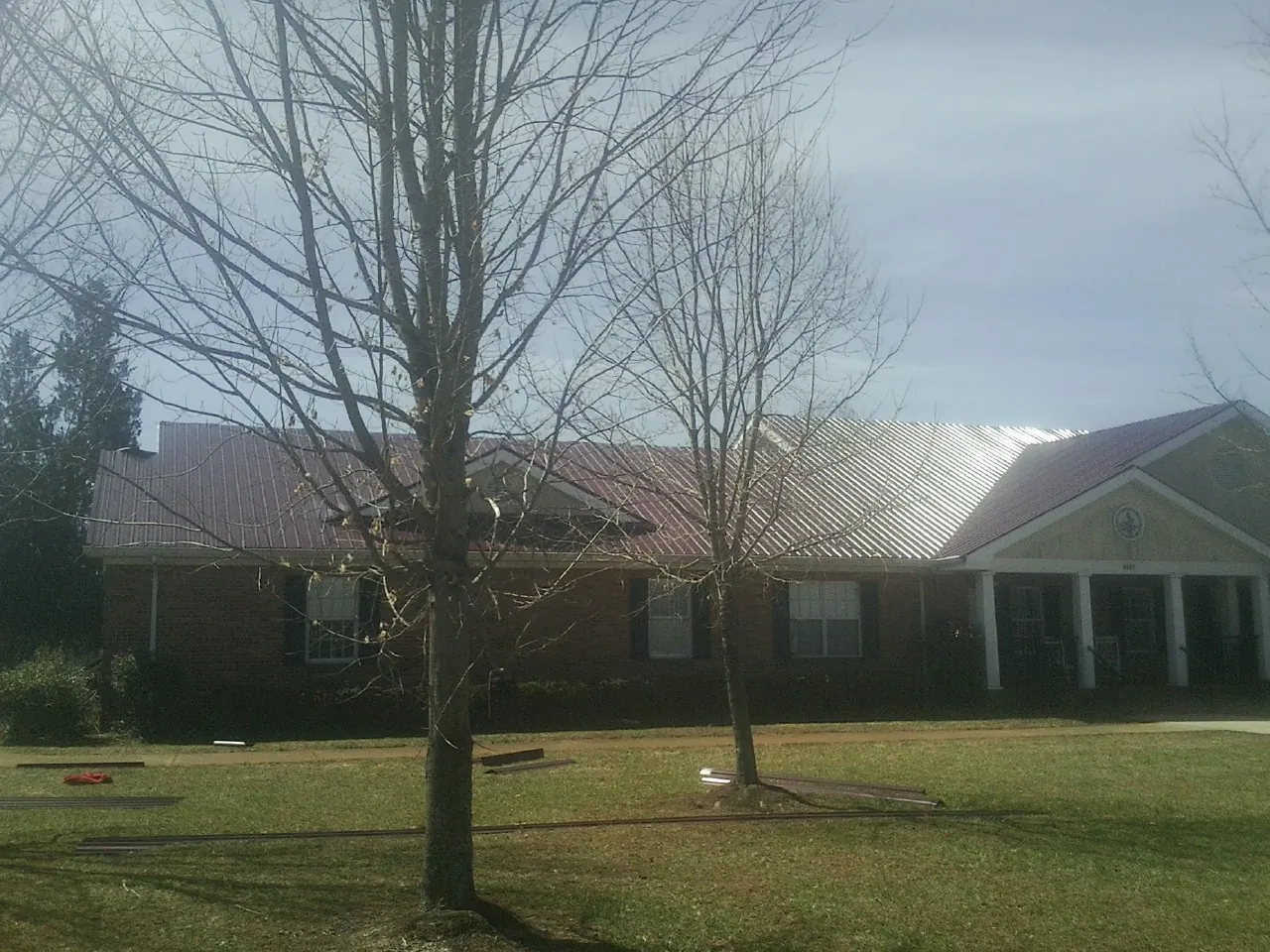 Red metal roof on a brick building seen from the front lawn in Park Ridge
