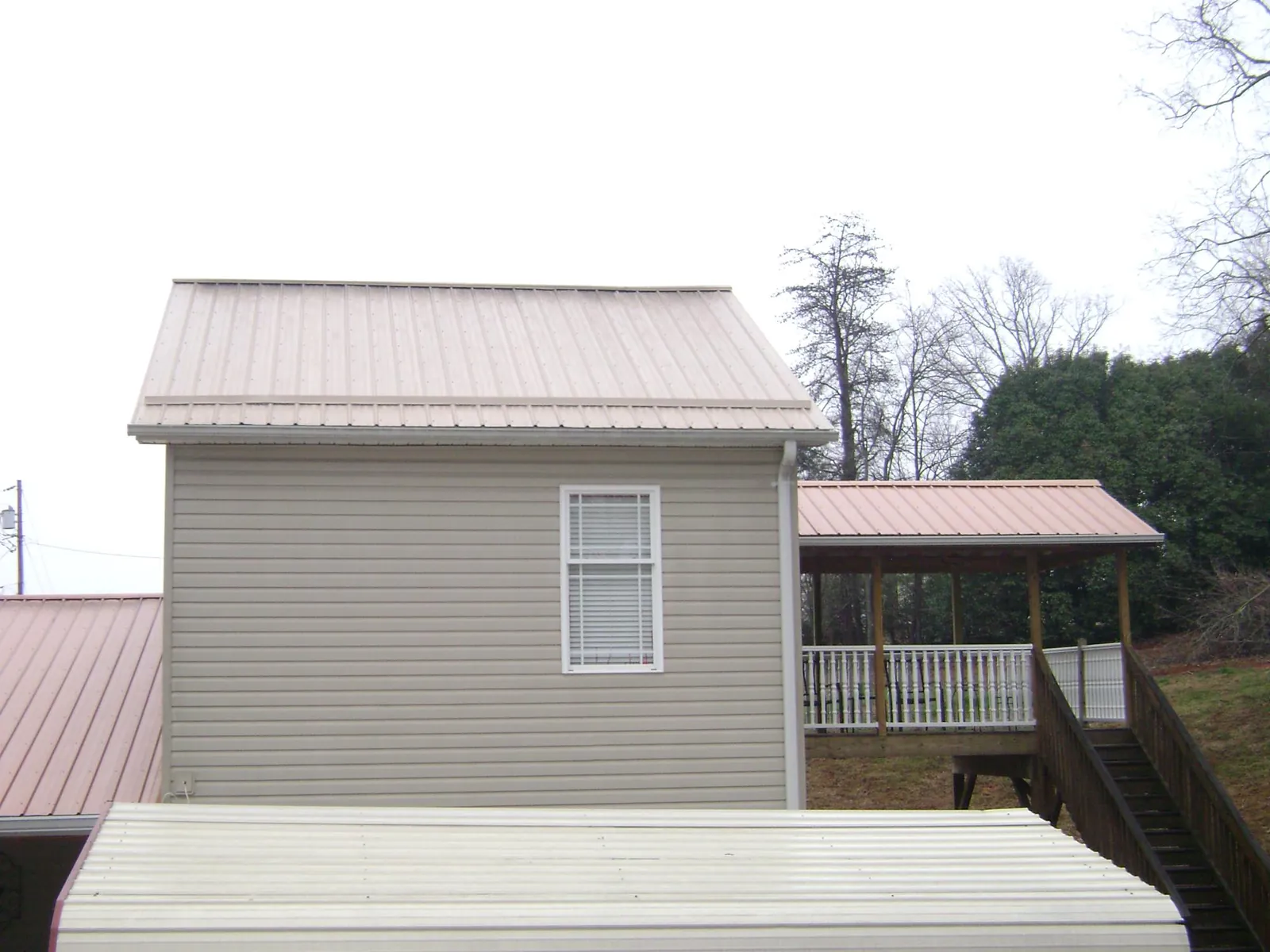 Tan metal roofs on a two story addition and attached porch, from a Roof Replacement job in Park Ridge